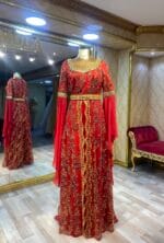 Vina kırmızı gold payet bindallı kına abiye elbisee - VznModa Red floor-length gown with gold embroidery on a mannequin, gold belt, in a luxury boutique. Paralleled mirror reflection visible in the background.