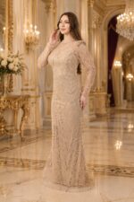 Elegant woman in a champagne beaded gown standing in a gilded, ornate ballroom hall.